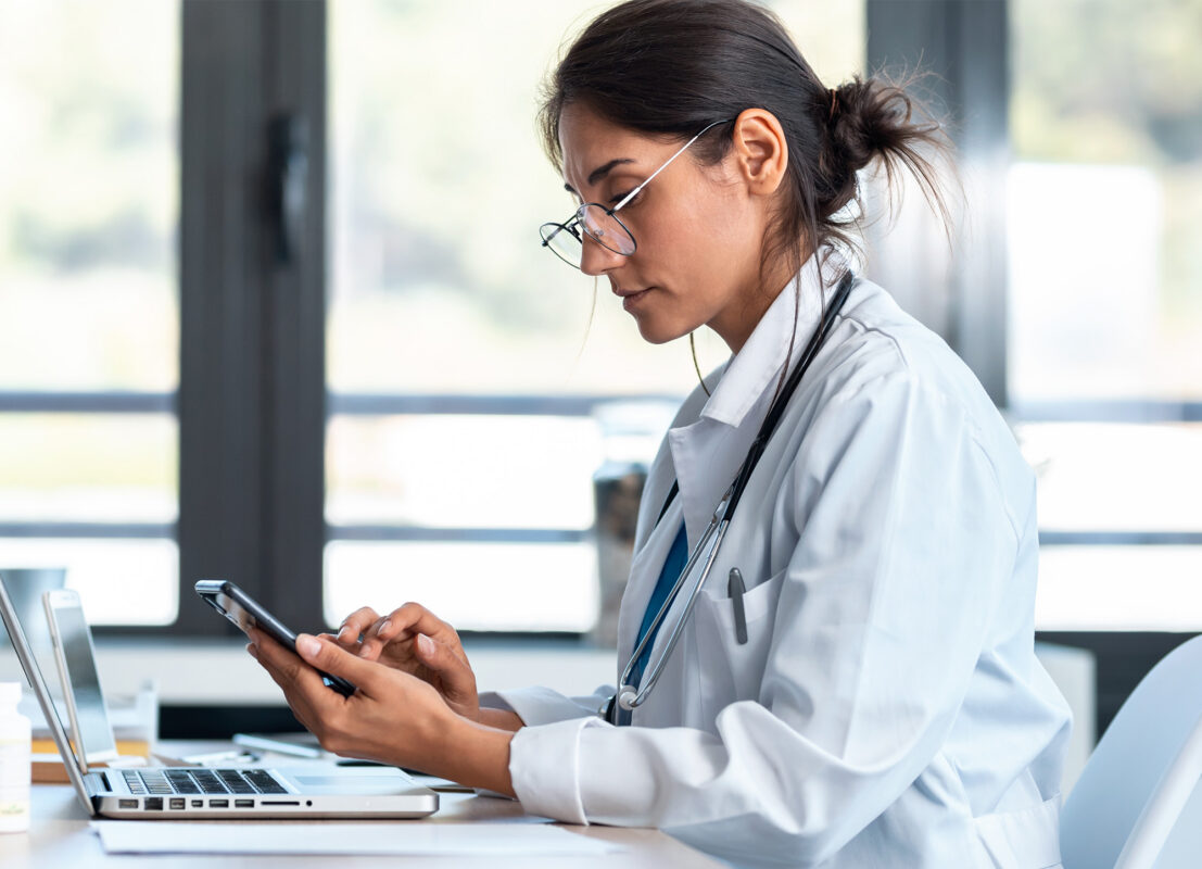 Doctor looks at phone for alerts